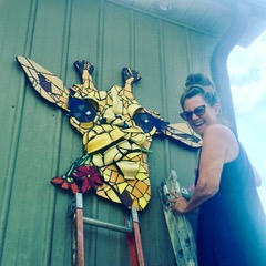 This image shows Lynn hanging the giraffe head on the facade of the Bell Buckle Mosaic House.