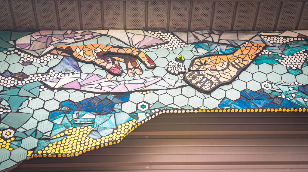 Colorful mosaic with image of a hand from the sky passing a gardenia to a another hand reaching from the sky.