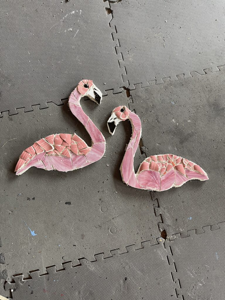 This image shows two pink mosaic flamingos prior to grouting.