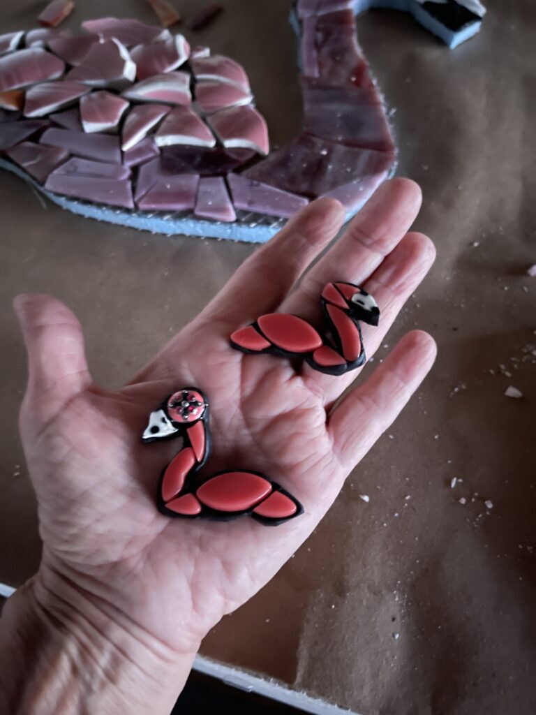 The image is two small 2" pink mosaic flamingos resting in a hand.