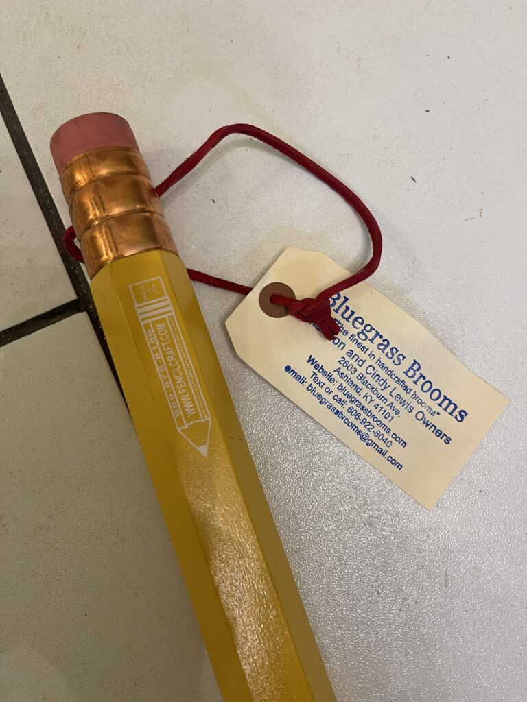 The image is of the eraser end of a large pencil that was made into a broom handle.